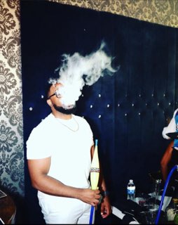 Man blowing a thick hookah smoke cloud at Moustache Hookah Lounge